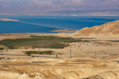 Ölü deniz tuzlu kıyısı. Endüstriyel deniz tuzu manzarası. Tuzlu plajlı bir arka plan, kıyı şeridinde tuzlu su. İsrail 'in Ölü Denizi' nin ortasındaki tuz madenciliği ve çıkarma alanı. Çöl, dağlar.