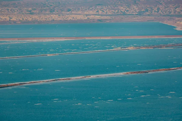 Dağlar ve mavi deniz manzarası. Endüstriyel tesisler. Pontoon madencilik potası ve Ölü Deniz 'den çamur. Tuz çıkarma, İsrail 'de üretim tesisi bölgesi. Sahil Ölü Deniz, tuz kristalleri plajı
