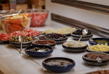 Taze yapılmış baharatlı soslar, biber, kırmızı biber ve zeytin tabakları. Odaklanmamış arka planda tuzlu atıştırmalıklar. Yemek için parti yemeği. Tahta masada yemek. Sığ alan derinliğine sahip seçici odak