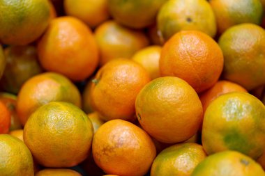Mandalina desenli arka plan fotoğrafı, odaklanmamış. Taze mandalina yığını, marketin tezgahında sulu narenciye. Noel, portakalları kapat, iyi şans simgesi olarak, yeni yıl havası.