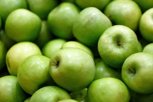 Stack of fresh green apples background, close up. Backgrounds of ripe juicy apples fruits from market. Picked apple, natural freshness, vegetarian food. Jewish New Year, Rosh Hashanah. Selective focus