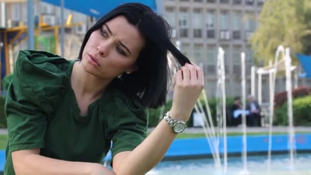 Serene Woman Fountain Park Her Hand Touches Her Hair Brunette — Stock Video