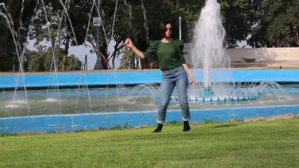 Egy Barna Lány Napszemüvegben Parkokban Táncol Zöld Pulóvert Farmert Visel — Stock videók