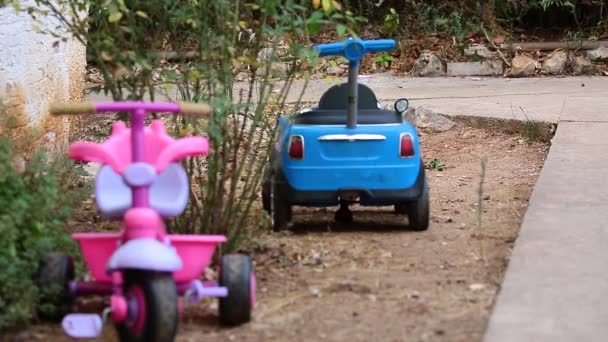 Два Яскравих Іграшкових Автомобілі Припарковані Саду Біля Будинку Час Легкий — стокове відео