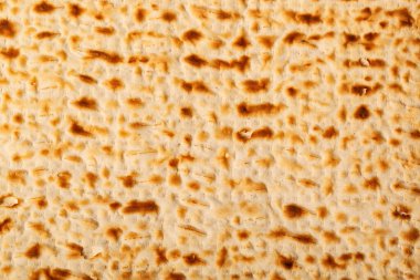 Matza 'ya yakından bak. Yahudi Hamursuz Bayramı' nda mayasız ekmek. Yüzey delinmiş ve kahverengileşmiş, pişmiş dokusunu vurguluyor. Hamursuz Bayramı hamuru, Yahudi mayasız matzo ekmeği..