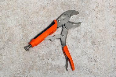 Döşeme kiremitlerinin üzerinde duran tek bir turuncu ve gri kerpeten. Bu araç genellikle nesneleri kavramak ve bükmek için kullanılır, elle manipülasyon gerektiren görevler için onu uygun hale getirir.