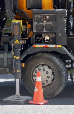 Ağır vasıtaların olduğu yere yakın durun. Büyük siyah bir lastik, sarı bir gövde ve düğmeleri ve kolları olan çeşitli kontrol panellerine sahiptir. Bir trafik konisi asfaltta lastiğin önüne yerleştirilir..