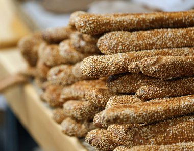 Altın kahverengi ekmek çubukları büyük ölçüde ahşap bir masada sergilenir. Taze pişmiş susamlı ekmekler güzelce sergileniyor. Susamlı taze İtalyan Grissini ekmeği.