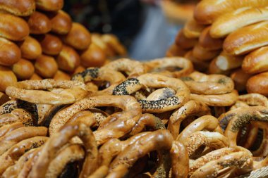 Fırından yeni çıkmış taze ekmek halkaları ve ruloları bir araya getirilerek çeşitli dokular sergileniyor. Susam ve haşhaş tohumlu altın, kabuklu somunlar, geleneksel fırın ürünlerini ön plana çıkarıyor..