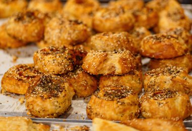 Bir fırında sergilenen susam tohumlu taze pişmiş hamur işleri. Kahverengi ikramlarda bol bol susam tohumu bulunur ve tuhaf dokuları sergilenir. Davetkar koku havayı dolduruyor.