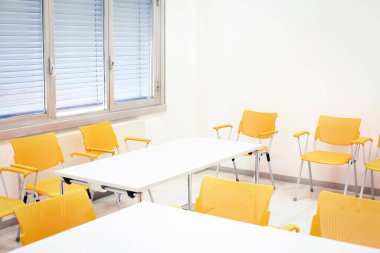 Odada sandalye ve masalar olan boş bir sınıf.
