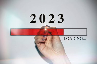 2023 'te kadın eli kalem tutarken, kadın eli de çubuğa yükleniyor.