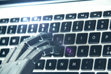 Bilgisayar klavyesinde çalışırken robot elin görüntüsü .