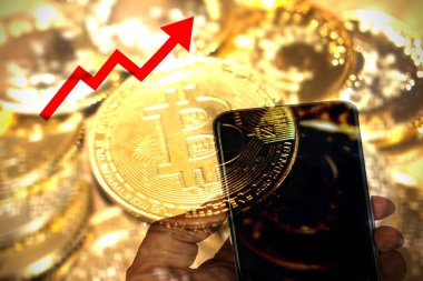 Arka planda altın bitcoin olan bir telefonu tutmak ve Bitcoin Fiyatının Artışı kavramının ok yukarı çıkması.
