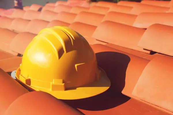 Professional Yellow hard hat on a house roof . Construction site concept.
