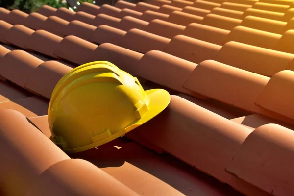 家の屋根の上に黄色いハード帽子 建設現場のコンセプト ストックフォト