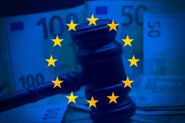 Avrupa Birliği bayrağı ve hakimin tokmağı arka plan olarak Euro parasıyla gri masanın üzerinde.