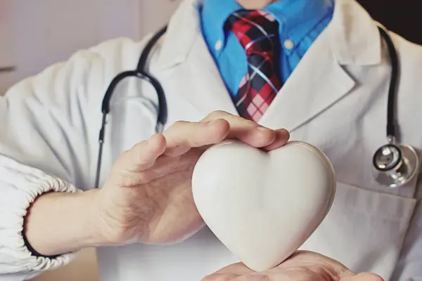 stock image Doctor holding a white heart . Concept of healthy lifestyle.