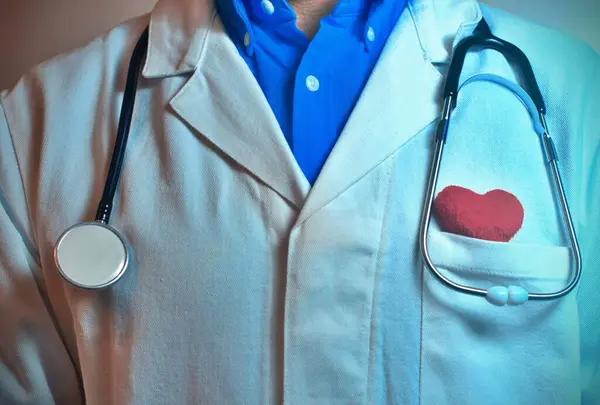Taking care of your heart. Cropped image of a doctor with heart shape toy inside the pocket while standing against grey background