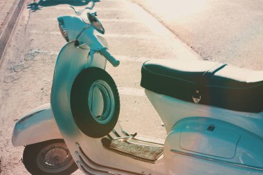 Eski model scooter gün batımında İtalya 'da bir sokakta park edilmiş. Beyaz İtalyan Klasik Motosikleti. Eski model bir motosikleti kapat..