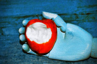 Bir ısırıkla elmayı tutan robot kol.