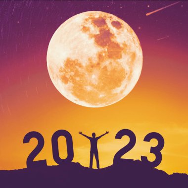 İnsanoğlu gün batımında dağın tepesinde dolunay ve 2023 numaralı soyut arkaplan ile el kaldırır. Mutlu yıllar ve tatil konsepti. Klasik ton filtre efekti renk biçimi.