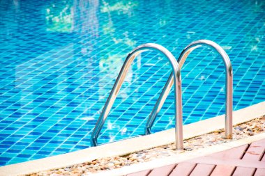 Yüzme havuzunda parmaklık merdiveni. Temiz suyla mavi kaplıca yüzme havuzu