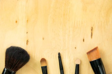 Ahşap arka planda makyaj fırçası. Güzellik ürünleri, üst görünüm, düz konsept.