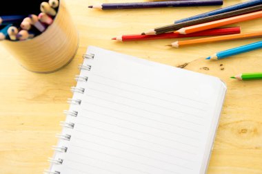 Üst görünüm defter kağıdı. Ahşap masadaki renkli kalemler.