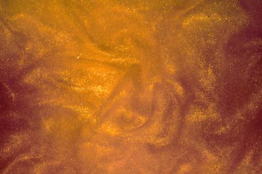 Koyu arkaplanda altın parıltı tozu.