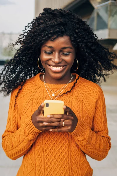 Smiling African American Woman Using Her Mobile Phone While Standing Stockfoto
