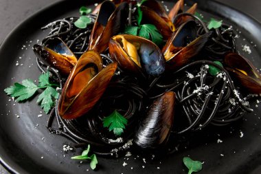 Spaghetti with black squid, black pasta, with boiled mussels, on a black plate, with parsley and parmesan cheese, close-up, selective focus, no people,