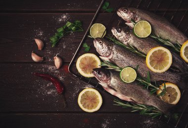 Raw rainbow trout, with lemon and herbs, on a wooden table, no people,