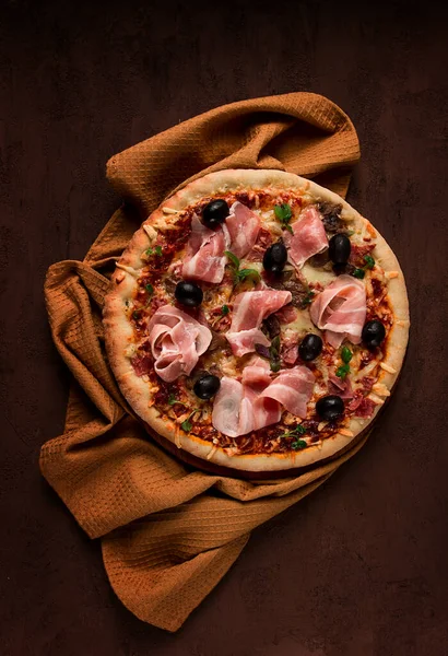 Pizza with prosciutto and mushrooms, bacon, olives, homemade, top view, no people,