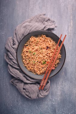 Instant noodles, in a bowl, on a gray table, top view, no people,