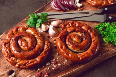 Fried spiral sausages, on a wooden board, top view, with spices, no people