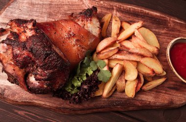 Pork knuckle, in soy-honey sauce, with fried potatoes, on a wooden chopping board, homemade, no people,