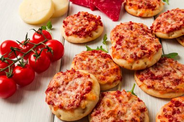 Mini pizzas, salami with mozzarella cheese, on a white table, top view, no people,