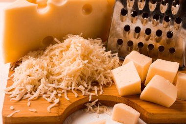 Grated cheese, Maasdam, on a cutting board, grater and cheese knife, close-up, no people,