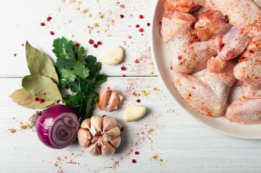 Fresh, raw chicken wings, with spices, on a white wooden table,