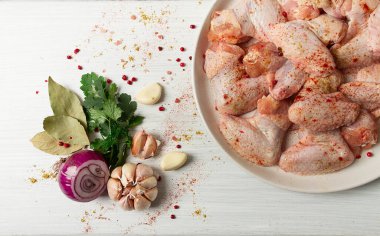Fresh, raw chicken wings, with spices, on a white wooden table,