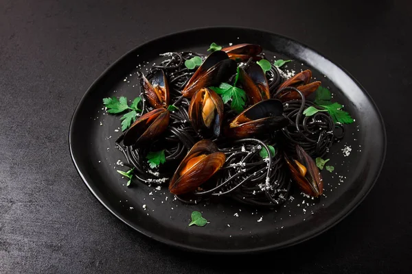 Spaghetti with black squid, black pasta, with boiled mussels, on a black plate, with parsley and parmesan cheese, close-up, selective focus, no people,