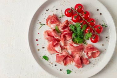 Dilimlenmiş prosciutto aperatifi, kiraz domatesli, beyaz tabakta, üst manzara.,