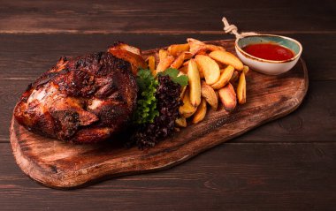 Pork knuckle, in soy-honey sauce, with fried potatoes, on a wooden chopping board, homemade, no people,