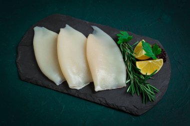 Taze mürekkep balığı bedeni, çiğ, üç leş, üst görünüm, siyah tahta üzerinde, insan yok.,