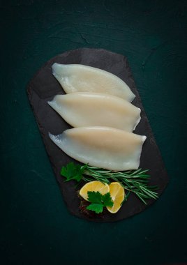 Taze mürekkep balığı bedeni, çiğ, üç leş, üst görünüm, siyah tahta üzerinde, insan yok.,