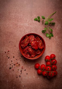 Kahverengi arka planda, üst manzaralı bir kasede kurutulmuş domatesler.,