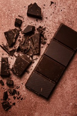 Çikolata imalatı için çikolata, kırık, parçalanmış, kahverengi arka planda, üst görünümde.,