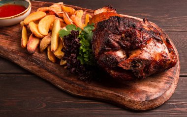 Pork knuckle, in soy-honey sauce, with fried potatoes, on a wooden chopping board, homemade, no people,