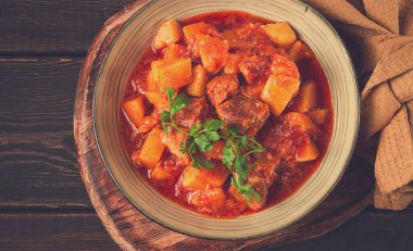 Patatesli, domates soslu, baharatlı ve otlu, yakın plan, insan yok, siyah arka planda.